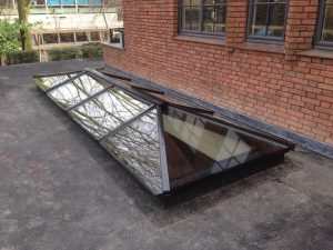Zwarte lichtstraat zadeldak met wolfseinden schilddak Jan de Bouvrie op plat dak.