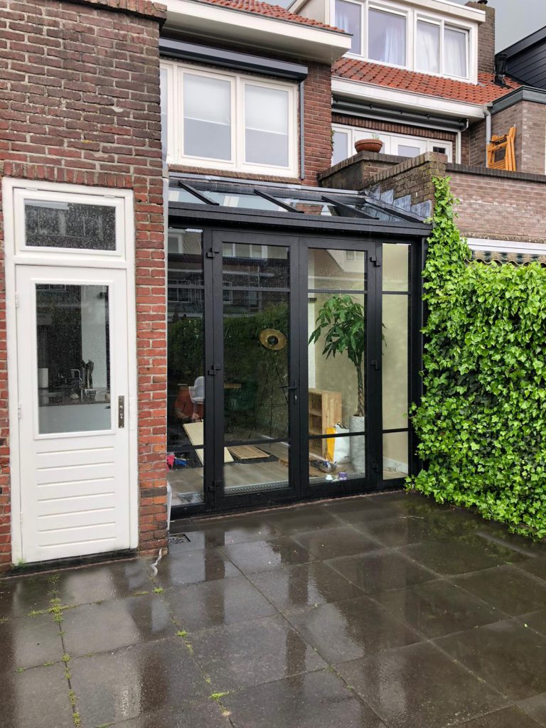 Een kleine serre met glazen lessenaarsdak