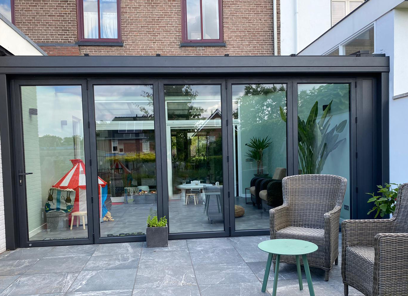 Vouwwanden aan donker grijze serre met glas
