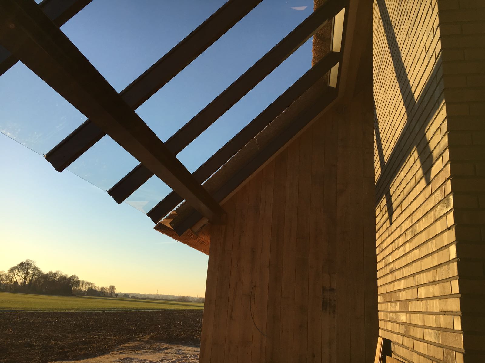 Glazen Terrasoverkapping aan de zijkant van een woning met houten zijmuur