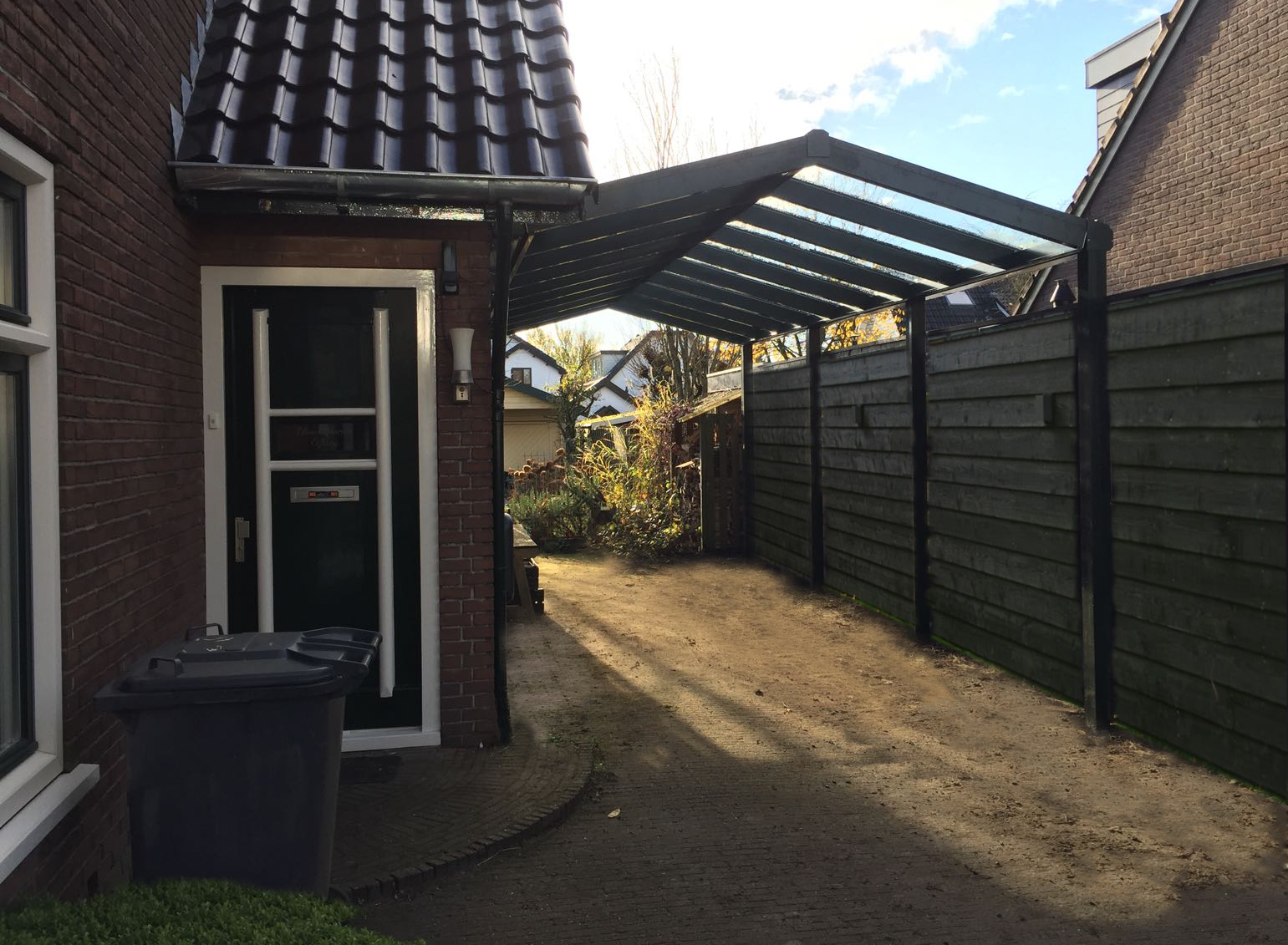 Zwarte zadeldak carport aan zijkant van woning