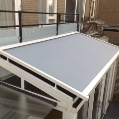 Grijze zonwering schuifpui over lessenaars dak witte serre