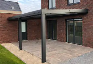 Zwarte terrasoverkapping aan gevel met glazen lessenaars dak aan gevel van huis. Terrasoverkapping ook mogelijk als carport aan de woning