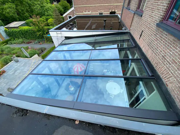 Grijze serre met lessenaar dak en vouwwand na het vervangen van het glas