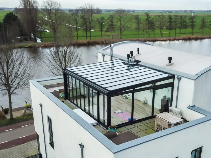 Zwarte dakterras serre met lessenaars dak boven op woning