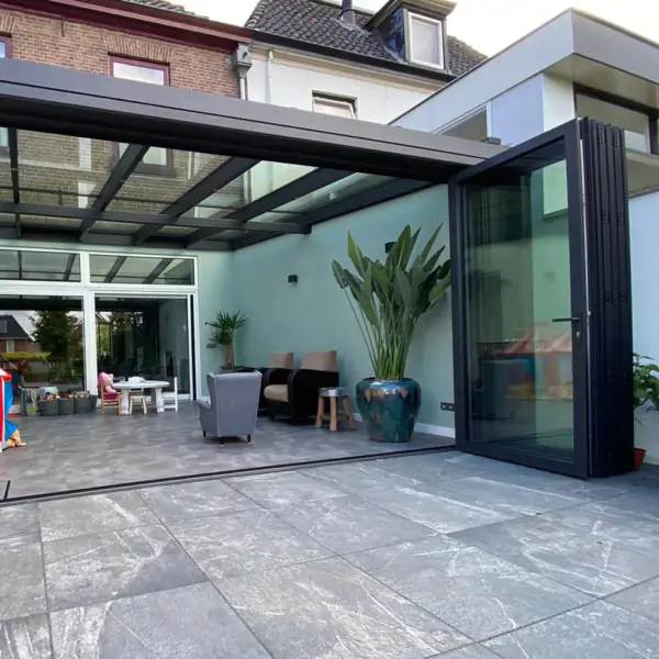 Buitenaanzicht serre: een patio met een glazen deur en een tafel.