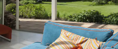 Serre-aanbouw aan een rijtjeshuis met een woonkamer met een blauwe bank en oranje kussens