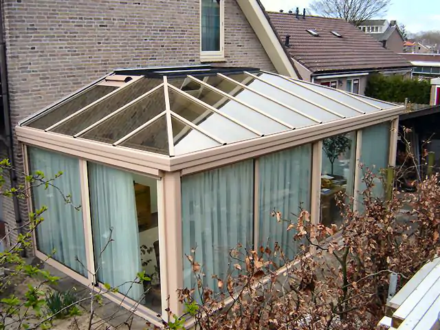Een serre met schuifwand en patio, omgeven door glas.