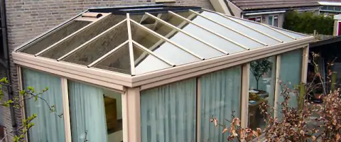 Een serre met schuifwand en patio, omgeven door glas.