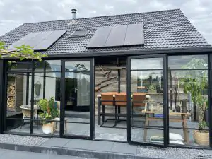 Zwarte serre/tuinkamer met plat dak en openslaande deuren