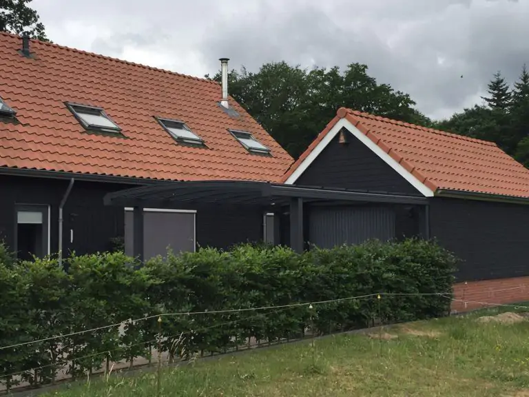 Zwarte gebogen carport voor zwarte houten garage.