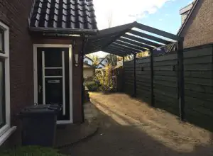 Donker groene carport zadeldak aan zijkant van woning, carport met puntdak