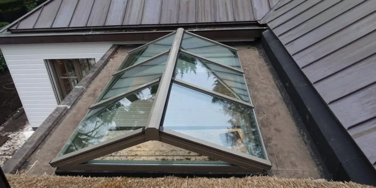 Aluminium zadeldaklichtstraat op een plat dak met meerdere glasvlakken en een centrale nok.
